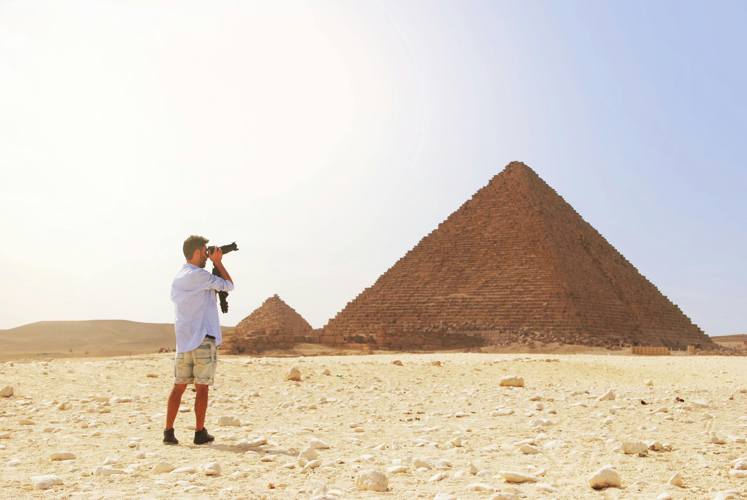 Photographer taking a picture of the Pyramid of Giza under the bright Egyptian sun.Hani- travel - резервирайте lux- аранжмани Hugrada Egipet, all inclusive , пирамидиHani- travel - резервирайте lux- аранжмани Hugrada Egipet, all inclusive , пирамиди