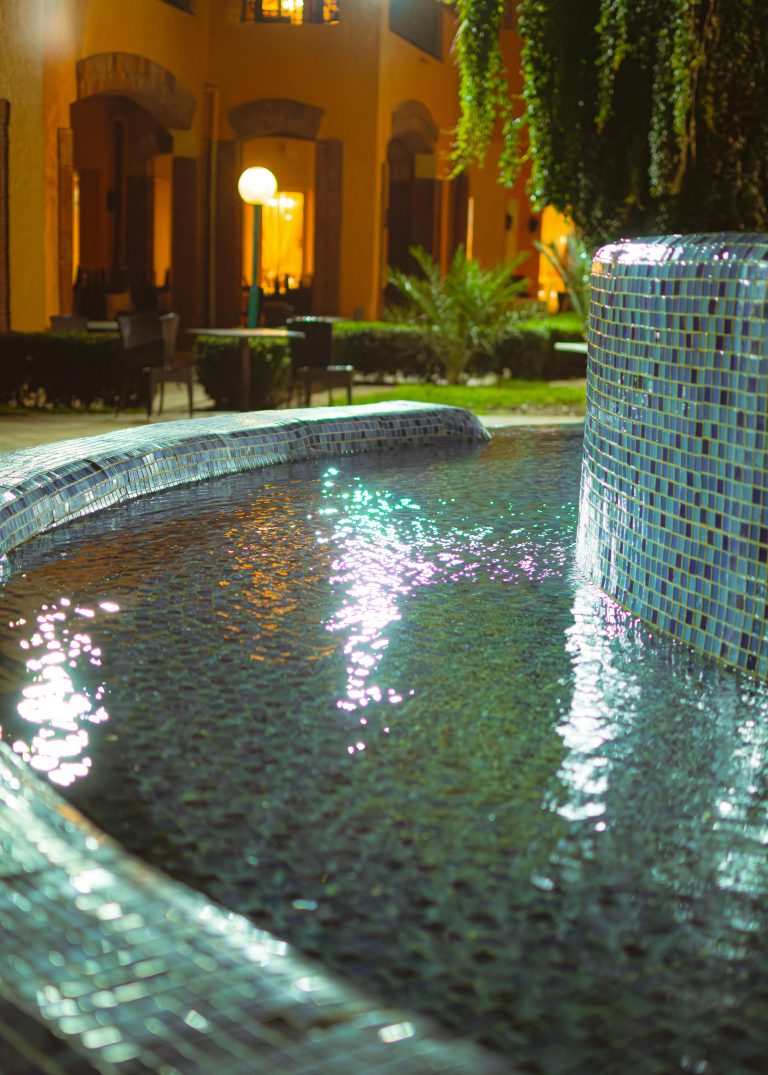 A serene night view of a reflective poolside in Tabarka, Tunisia, capturing ambient lighting.Хани Травел - летни аранжмани -Тунис